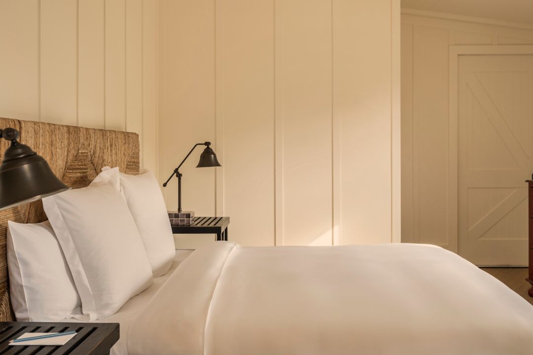 Bedroom in a two bedroom hotel suite with plush bed, bedside tables with lamps and dresser.